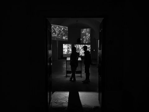 La sala della mostra con le proiezioni su cinque schermi e due visitatori